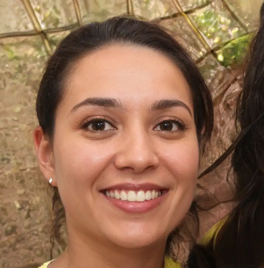 Two women pose together outdoors, smiling, with lush green foliage and a natural background behind them. Both wear casual, bright tops.